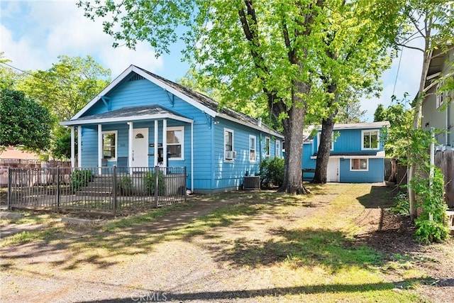 view of front facade with a porch, fence, and cooling unit