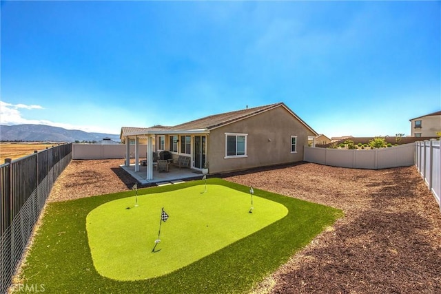 back of property with a fenced backyard, a patio area, stucco siding, and a mountain view