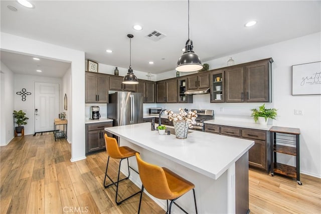 kitchen with under cabinet range hood, appliances with stainless steel finishes, visible vents, and light countertops