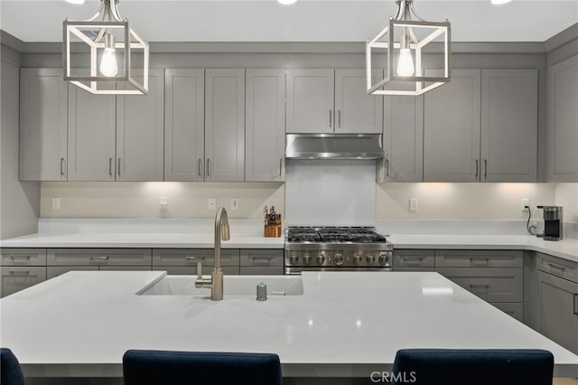 kitchen featuring light countertops, stove, under cabinet range hood, and gray cabinetry