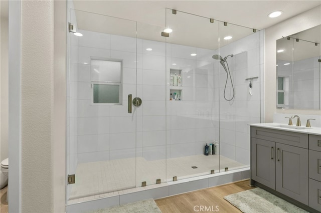 bathroom with vanity, toilet, wood finished floors, and a stall shower
