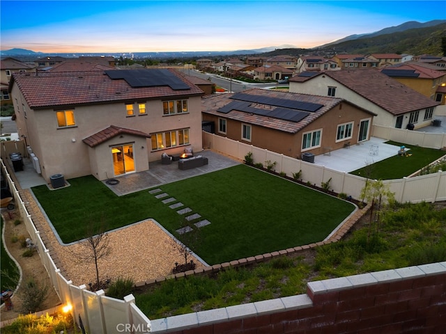 back of house at dusk with a tiled roof, a residential view, solar panels, and stucco siding