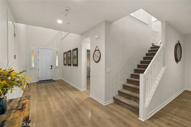 foyer with baseboards, recessed lighting, wood finished floors, and stairway