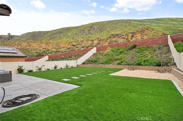 view of yard with a fenced backyard, a mountain view, and a patio area