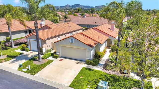 40684 Corte Albara, Murrieta, CA 92562 - view of front of house featuring stucco siding, a chimney, a tiled roof, concrete driveway, and an attached garage