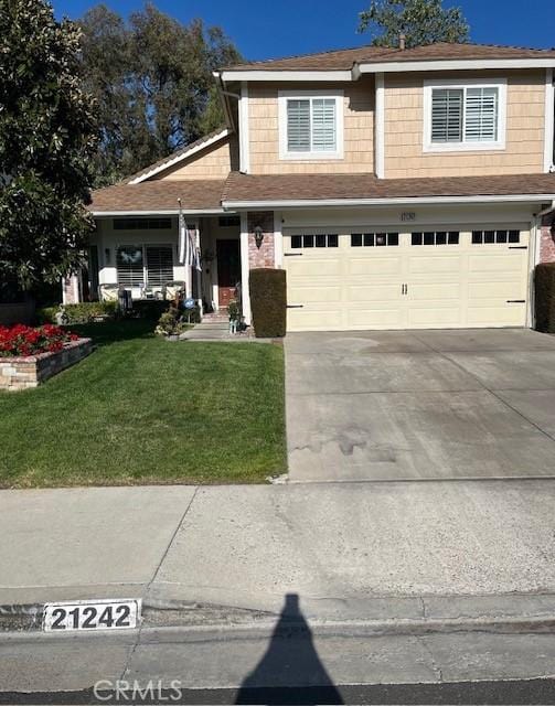 view of front of home with an attached garage, driveway, and a front yard