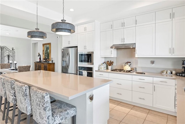 32148 Sedge Way, Temecula, CA 92591 - kitchen featuring appliances with stainless steel finishes, under cabinet range hood, white cabinets, decorative light fixtures, and light countertops
