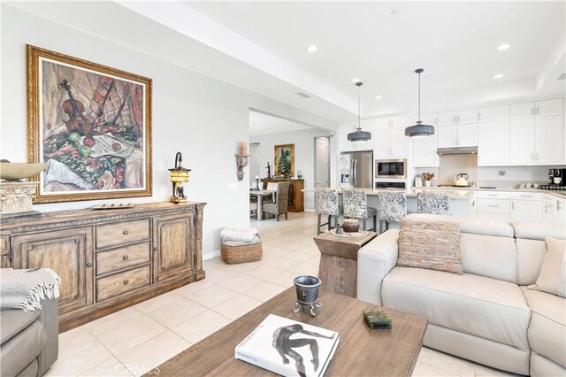 living area with light tile patterned flooring, recessed lighting, and a raised ceiling