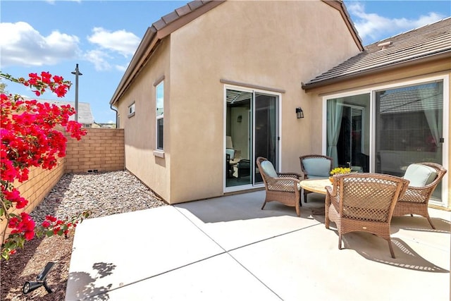 rear view of house featuring stucco siding, a patio area, fence, and a tile roof