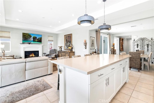 kitchen with light tile patterned floors, a center island, white cabinetry, and open floor plan