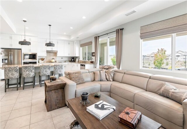 living area featuring visible vents, recessed lighting, light tile patterned floors, and a tray ceiling