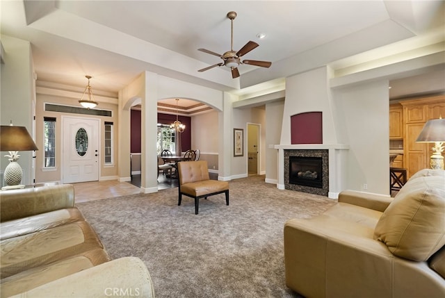 14124 Rollins Ct, Magalia, CA 95954 - living room featuring ceiling fan with notable chandelier, arched walkways, light carpet, and a tray ceiling