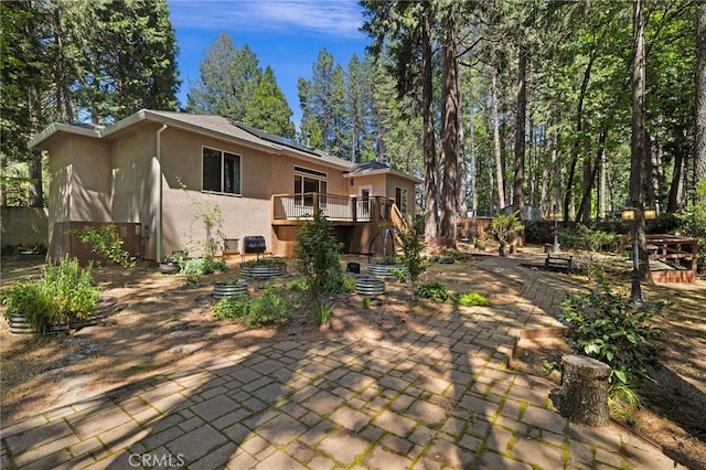 14124 Rollins Ct, Magalia, CA 95954 - rear view of house with a patio, a wooden deck, roof mounted solar panels, and stucco siding