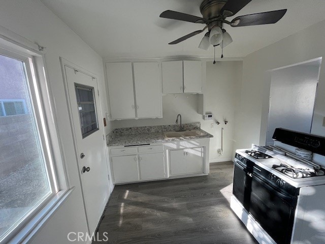 kitchen featuring range with gas cooktop, a ceiling fan, dark wood-style flooring, a sink, and white cabinetry