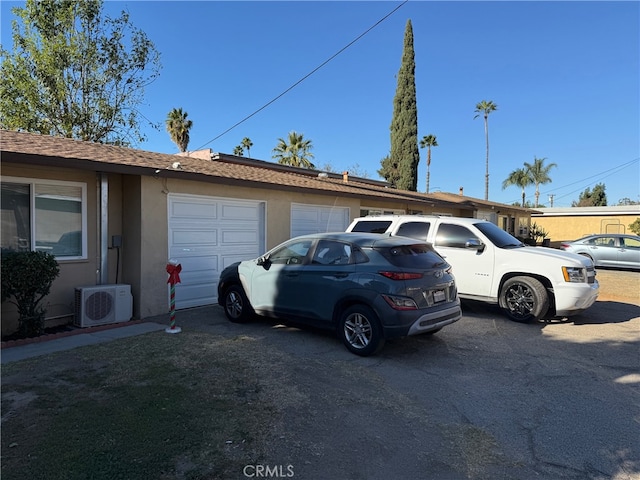 exterior space featuring a garage, ac unit, and stucco siding