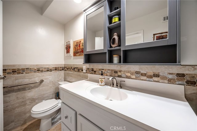 bathroom featuring wainscoting, vanity, toilet, tile walls, and visible vents