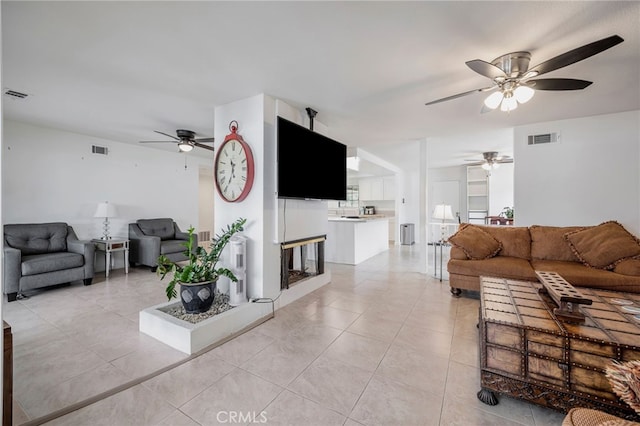 living area featuring light tile patterned floors, a ceiling fan, and visible vents