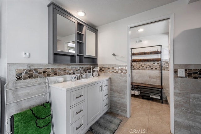 full bathroom featuring visible vents, tile walls, wainscoting, vanity, and tile patterned floors