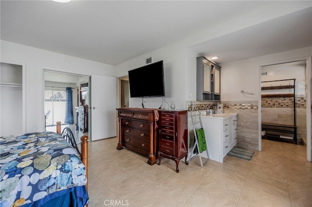 bedroom featuring light tile patterned floors, tile walls, and wainscoting