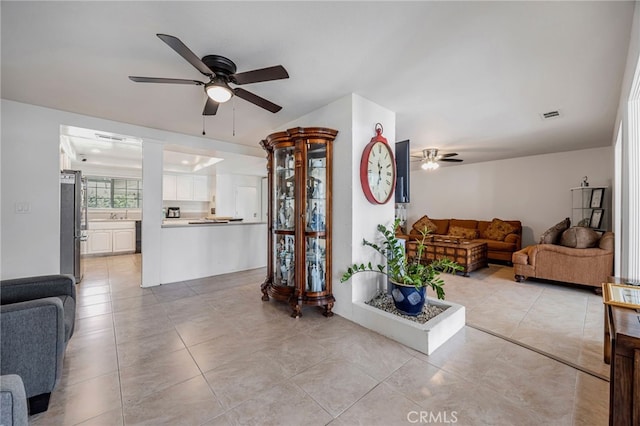 living room with a ceiling fan, visible vents, and light tile patterned floors