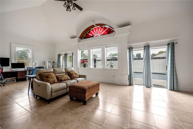 tiled living area with a ceiling fan, high vaulted ceiling, and baseboards