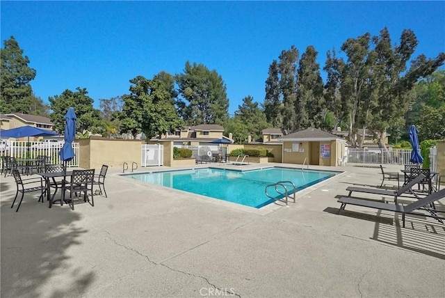 pool with a patio area and fence