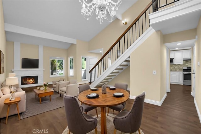 dining area with a brick fireplace, dark wood-style flooring, baseboards, and stairway