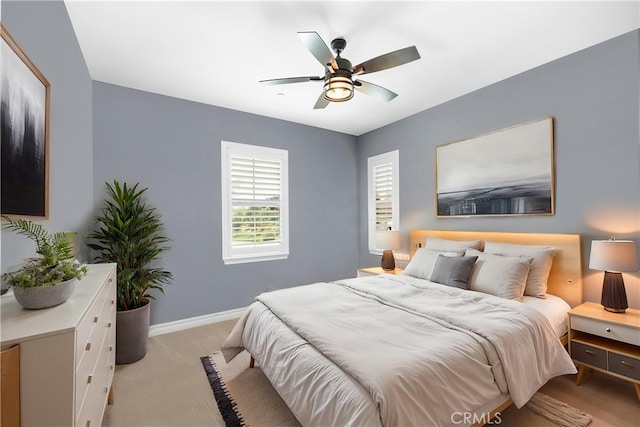 bedroom featuring baseboards, light carpet, and a ceiling fan