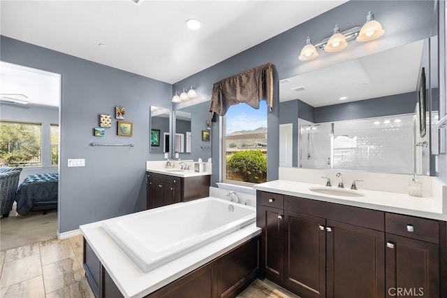 bathroom featuring two vanities, a shower stall, a sink, and a garden tub