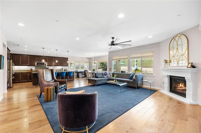 living room with light wood-style floors, recessed lighting, a glass covered fireplace, and ceiling fan