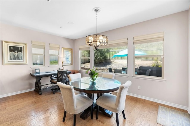 dining area with baseboards, light wood-style floors, and a notable chandelier