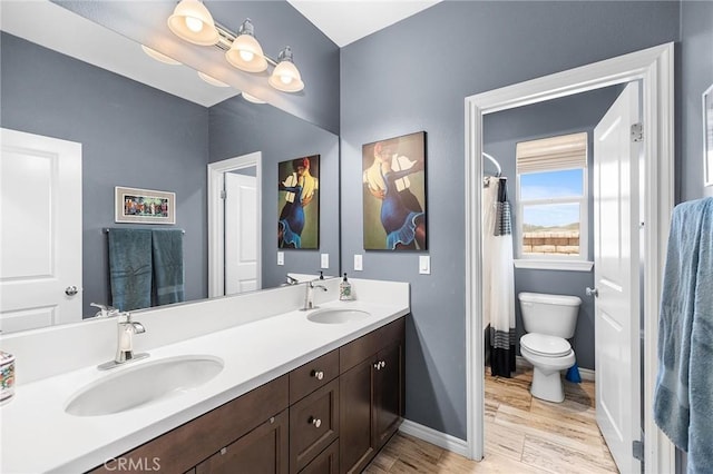 bathroom with toilet, baseboards, a sink, and wood finished floors