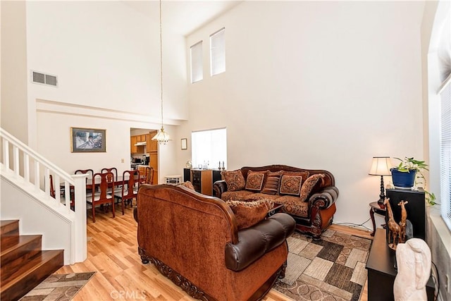 living area with visible vents, stairs, a high ceiling, and light wood-style floors