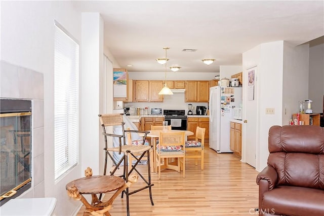 kitchen featuring freestanding refrigerator, visible vents, light wood-style flooring, and black range with electric stovetop