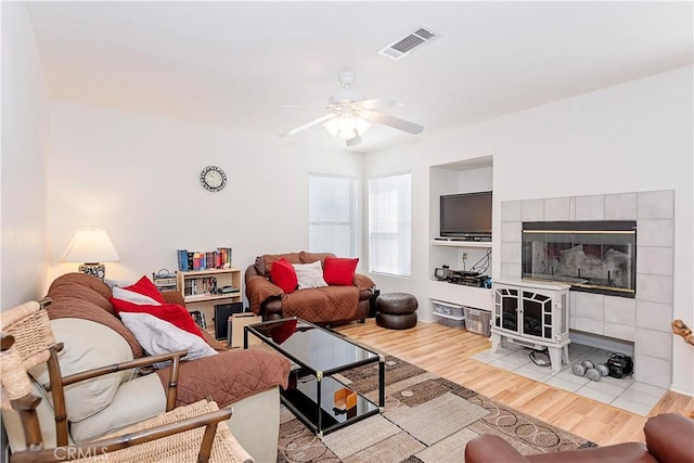 living area with a ceiling fan, visible vents, and wood finished floors