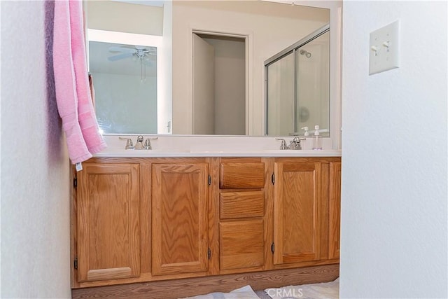 bathroom with double vanity, a sink, ceiling fan, and a shower stall