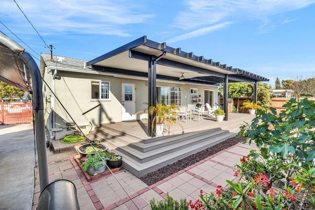 back of property with fence, a wooden deck, and stucco siding