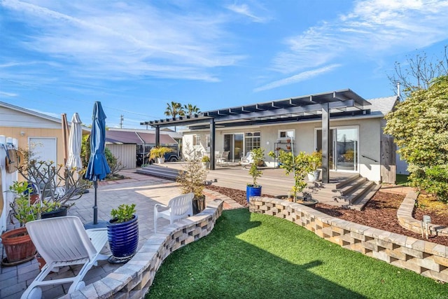 back of property featuring a pergola, a wooden deck, stucco siding, a patio, and a yard