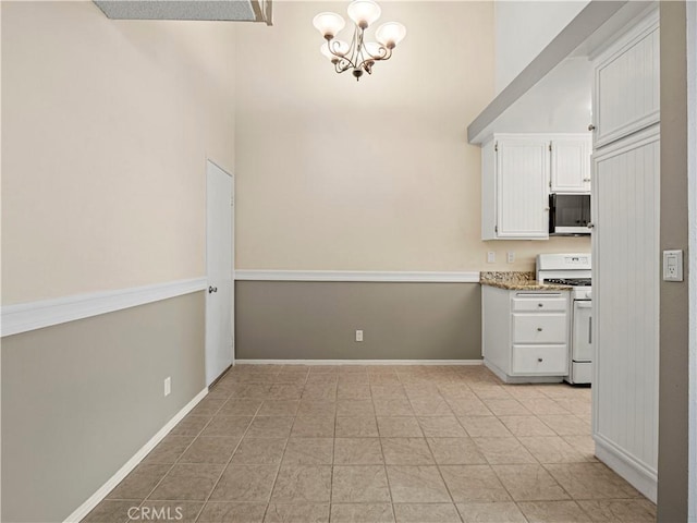 kitchen with an inviting chandelier, white cabinetry, white range with gas stovetop, light tile patterned floors, and a towering ceiling