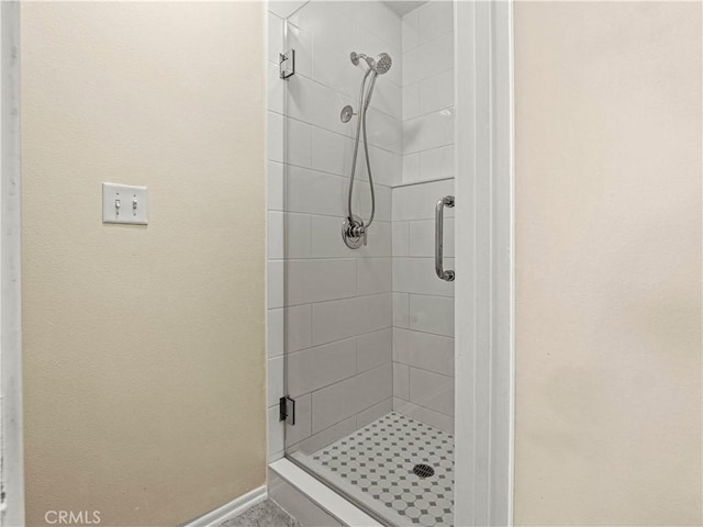 bathroom with baseboards and a stall shower