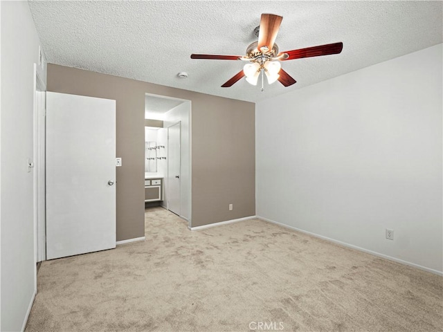 unfurnished bedroom featuring light colored carpet, a textured ceiling, ensuite bathroom, and baseboards