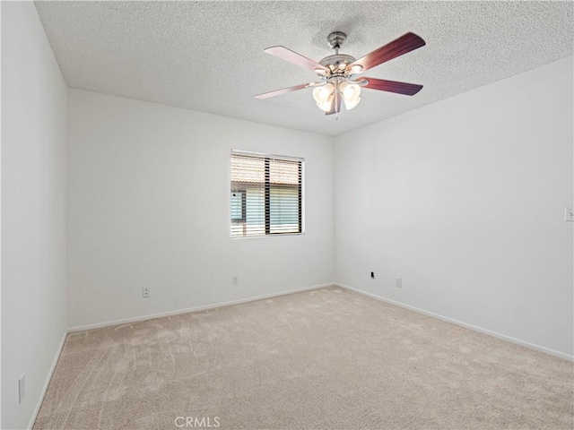 empty room featuring a textured ceiling, ceiling fan, light colored carpet, and baseboards