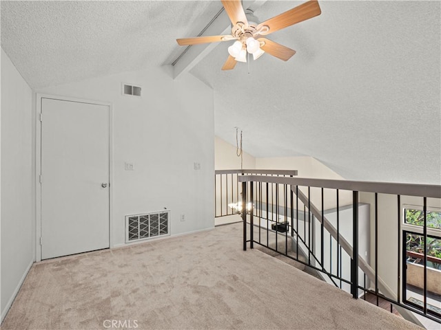 interior space with visible vents, a ceiling fan, a textured ceiling, and vaulted ceiling with beams