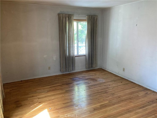 empty room featuring baseboards and hardwood / wood-style floors