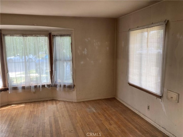 spare room with baseboards and hardwood / wood-style floors