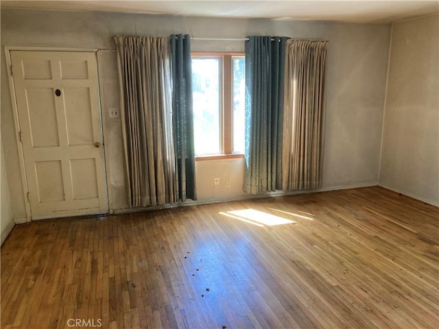 empty room with wood-type flooring and baseboards