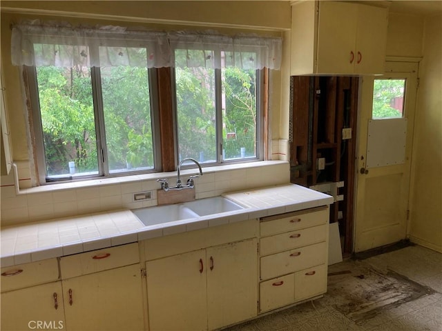 kitchen with tile counters, a healthy amount of sunlight, and a sink