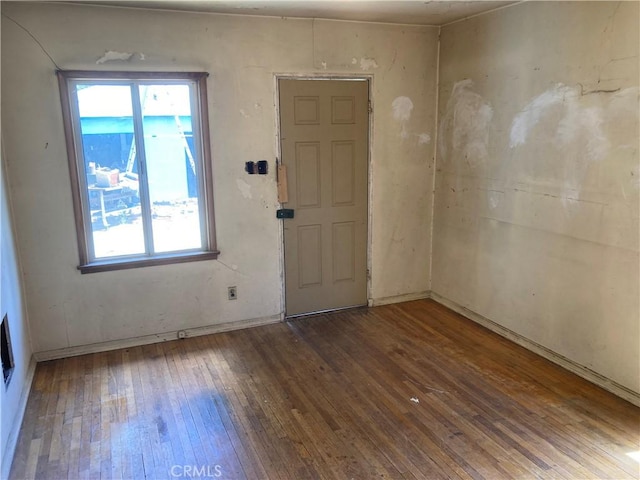 unfurnished room featuring baseboards, hardwood / wood-style floors, and a wealth of natural light