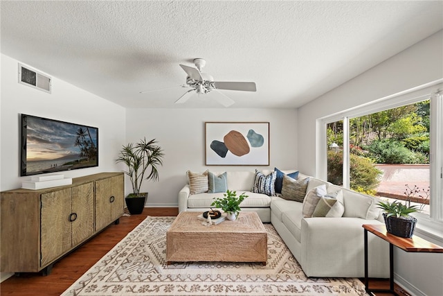 living area featuring dark wood-type flooring, ceiling fan, a textured ceiling, and baseboards