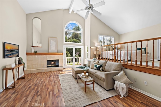living room featuring high vaulted ceiling, ceiling fan, wood finished floors, baseboards, and beamed ceiling